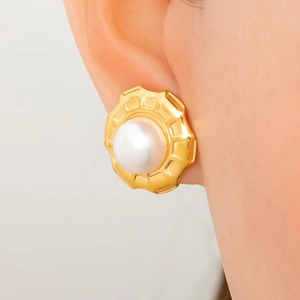 Elegant 18K gold-plated pearl stud earrings with textured gold rim worn by a model