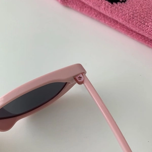 Close-up of the metal screw hinge on premium pink cat-eye sunglasses with dark lenses