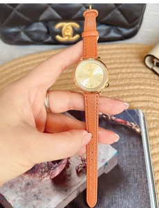 Detailed close-up of orange leather strap and gold diamond-encrusted bezel watch