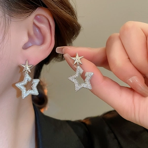 Close-up of silver star earrings with pavé cubic zirconia worn by a model