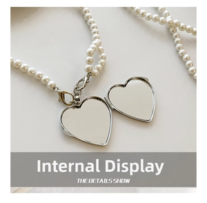 Macro view of heart-shaped locket pendant with pearl chain showing inner mirror detail