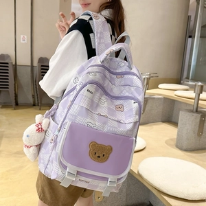 Purple plaid backpack with cute bear patterns and plush bunny charm on a female model