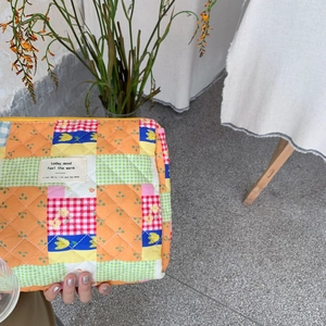 Close-up of quilted floral cosmetic bag featuring colorful patchwork and tulip patterns
