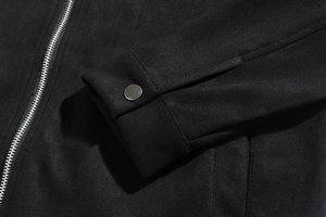 Close-up of metal zipper and silver button detail on black brushed suede jacket