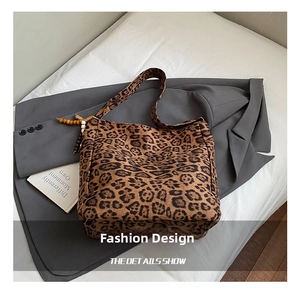 Detail of leopard print tote bag with beaded charm on dark grey blazer