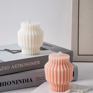 Detail of pleated geometric pillar scented candles in white and pink on decorative books
