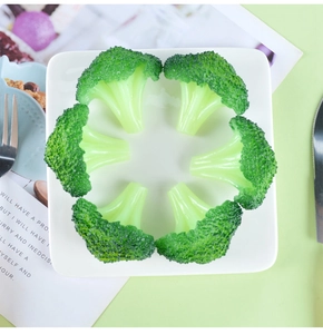 Close-up of six realistic artificial broccoli models arranged on a white ceramic plate