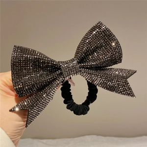 Detail of a black velvet bow hair tie decorated with sparkling dark rhinestones