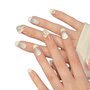 Silver glitter press-on nails with white 3D bows and French tips in oval shape