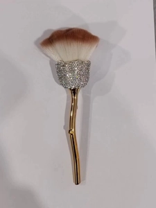 Detail of rose-shaped makeup brush with crystal-studded ferrule and golden stem