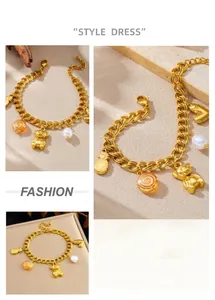 Détail du bracelet à double chaîne dorée avec pendentifs ours, ananas et cœur