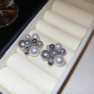 Macro shot of silver zircon firework flower earrings with white and grey pearls in a box