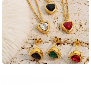 Detail of heart pendants with colorful zircon inlay and beaded gold edges on coral