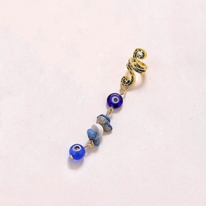 Detail of golden spiral cuff featuring a blue evil eye bead and natural stone pendant