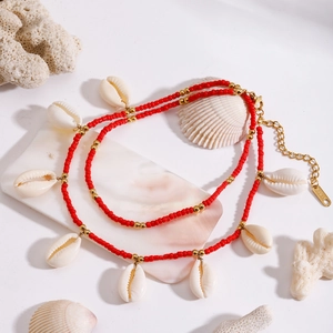 Detailed macro of stainless steel beach anklet with red beads and natural white shells