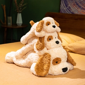 Three sizes of soft cream-colored plush toy dogs in a stack on a cozy bedroom bed