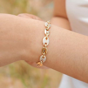 Detail of coffee bean link bracelet in gold finish with sparkling zircon stones