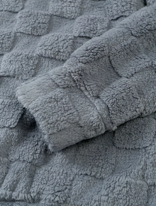 Gros plan d'une manche de sweat en peluche grise avec un motif à carreaux texturé