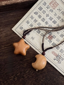 Detailed close-up of handmade wooden star and moon pendants on braided cord necklaces