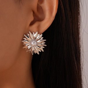 Close-up of silver sunflower earrings with a center pearl worn by a model