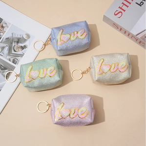 Close-up of four glitter love sequin coin purses in pastel blue green gold and pink colors