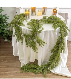 Lush green PE cedar garland draped on a festive table with candles and ornaments
