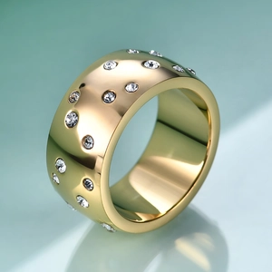 Macro view of wide gold plated cigar band ring with scattered sparkling round cubic zirconia