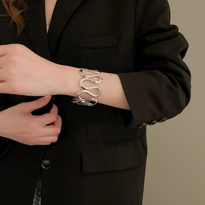Detail view of a silver wide wavy cuff bracelet with high-polish metallic finish