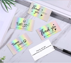 Detailed view of rainbow holographic thank you cards on a marble surface with desk decor