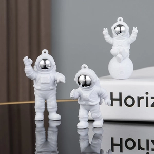 Three matte white astronaut pendants with silver visors as keychain accessories