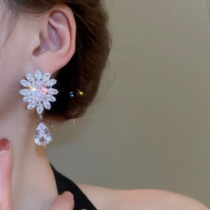 Close-up of flower and teardrop earrings with sparkling zircons worn by a model