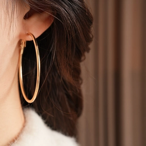 Close-up of model wearing large vintage gold hoop earrings with polished mirror finish