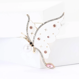 Elegant butterfly brooch with white enamel, pink gems, and star details on a stand