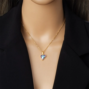 Collier chic à pendentif cœur doré et strass dégradés porté avec un blazer noir chic