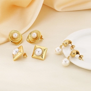Detailed close-up of gold titanium steel earrings with pearls on silk and porcelain