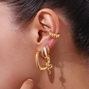 Detailed close-up of 18K gold-plated snake charm earrings and white enamel ear studs set