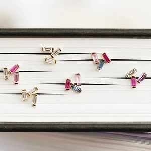 Artistic layout of gold rectangular gemstone studs nestled between book pages