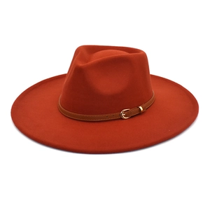 Dettaglio di un cappello fedora in lana arancione con cinturino marrone e fibbia oro