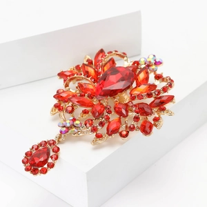 Détail de broche fleur aux cristaux rouges et finition dorée sur support blanc