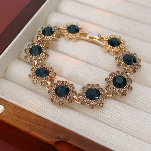 Detail of vintage gold flower bracelet with dark blue gemstones and rhinestones