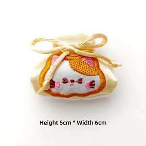 Détail d'une mini pochette en satin jaune avec broderie chat et dimensions de 5 cm sur 6 cm