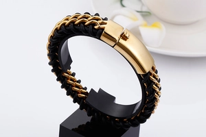 Detail of woven black leather and gold steel chain bracelet with magnetic clasp