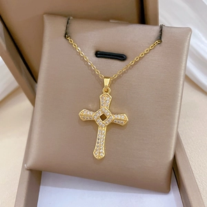 Detailed view of a gold spinning cross necklace with crystals on a beige display pad