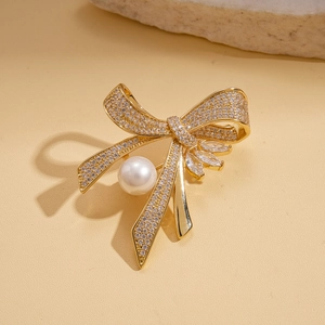 Detailed view of a gold bow brooch with micro-pave zircons and a large round white pearl