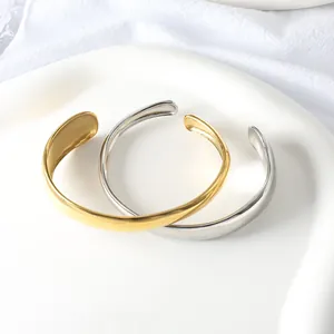 Detailed macro view of gold and silver minimalist C-shaped stainless steel cuffs