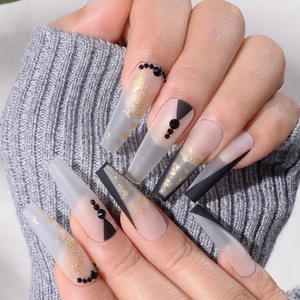Macro detail of long coffin press-on nails with gold foil, black geometric art and rhinestones
