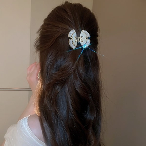 Dettaglio dell'elegante molletta a farfalla con zirconi e madreperla su capelli castani