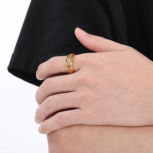 Detailed close-up of a men's gold ring with grid texture and a single inset diamond