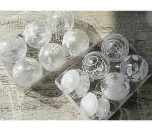 Close-up of clear and white 6cm snowflake Christmas balls in PVC boxes on wood surface