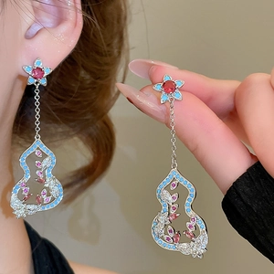 Detailaufnahme der silbernen Ohrringe in Kürbisform mit funkelnden rosa und blauen Zirkonia